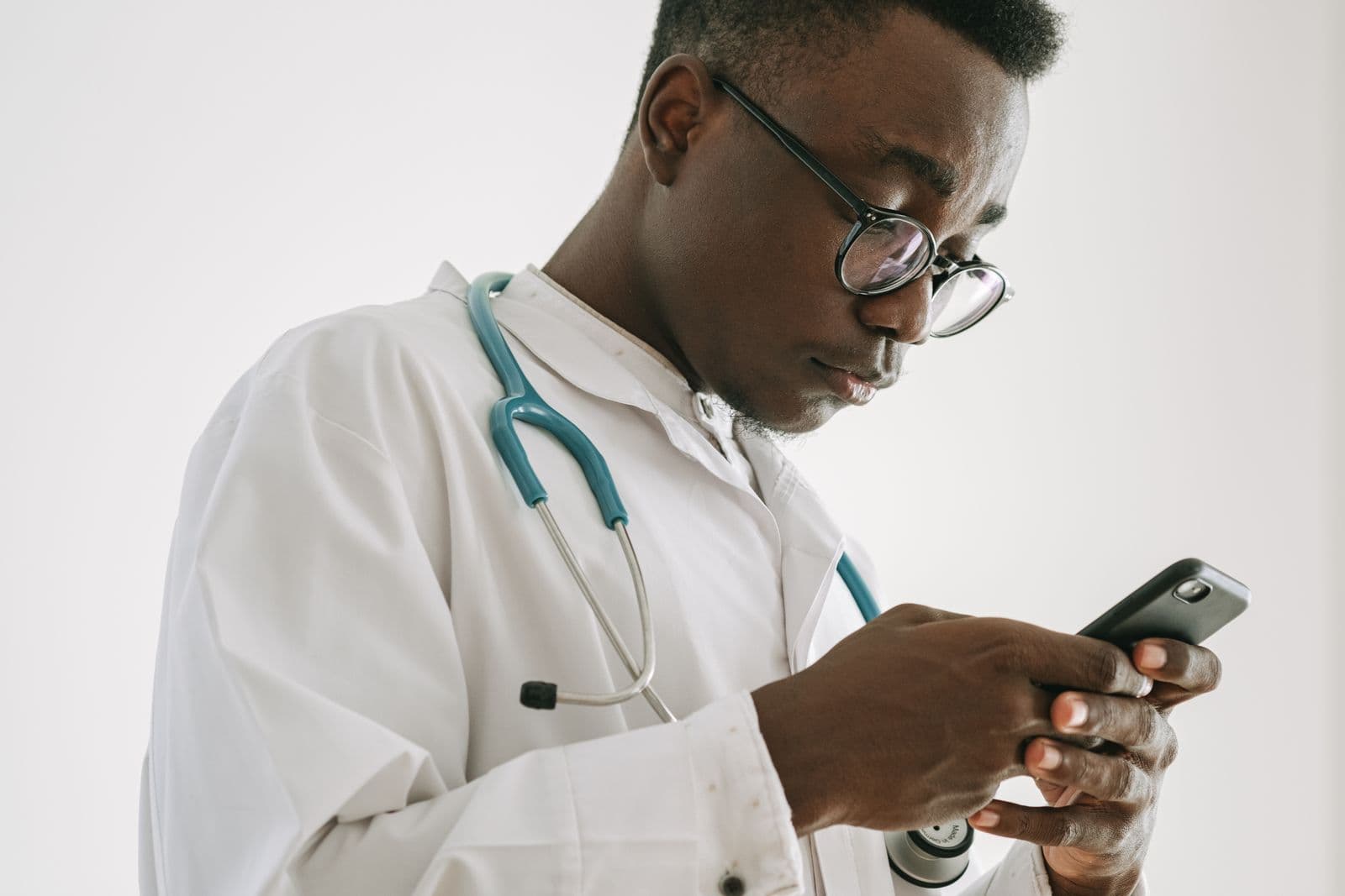 A doctor in a white coat checking a phone