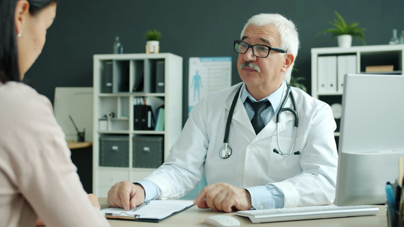 A doctor and patient shaking hands across a desk